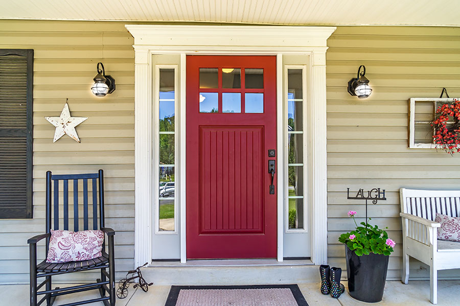 About Our Agency - View of the Front Porch of a Farmhouse with a Red Door and a Rocking Chair