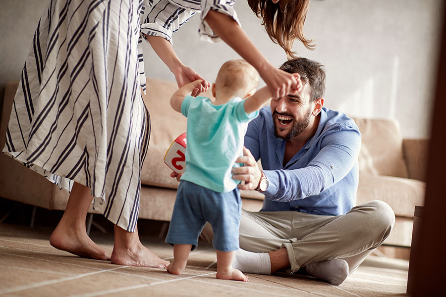 Individual Life Insurance - Excited Mother and Father Teaching Their Toddler How to Walk in the Living Room